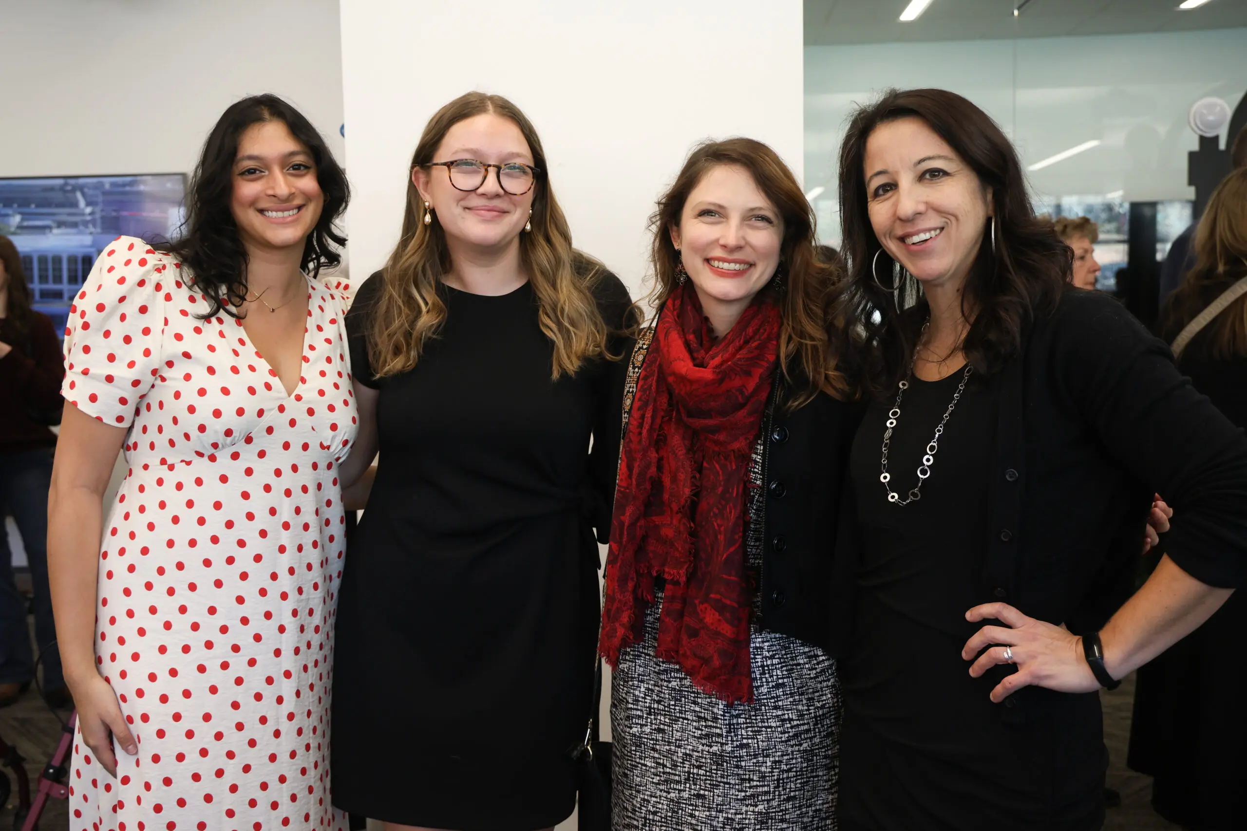 Four women poses for a picture in a room.